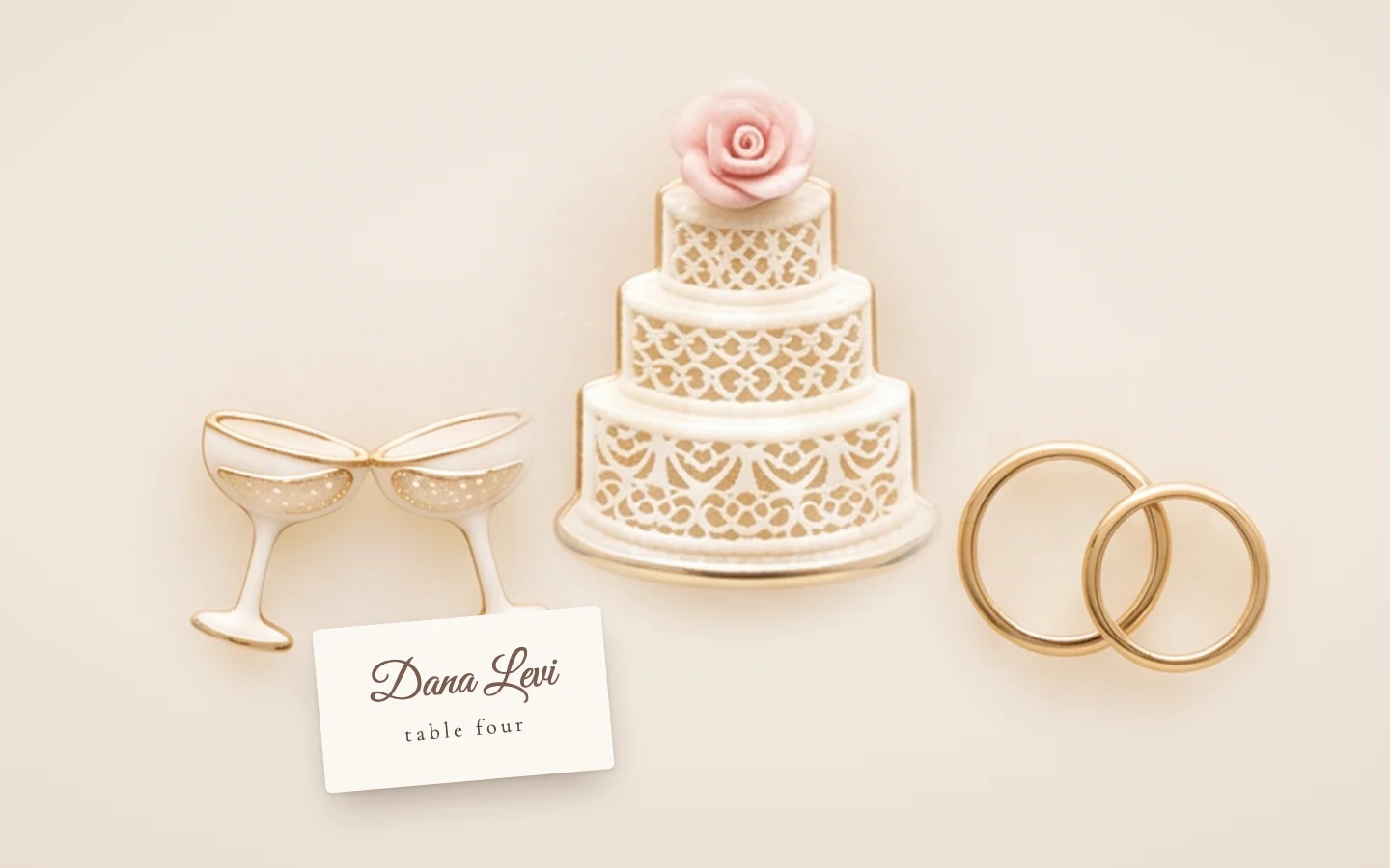 Two champagne coupes, a tiered white cake and a pair of wedding rings sculpted in sugar, on soft pink silk